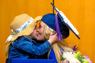Kayley Sisler shares a sweet kiss with her daughter, Myah, following commencement.